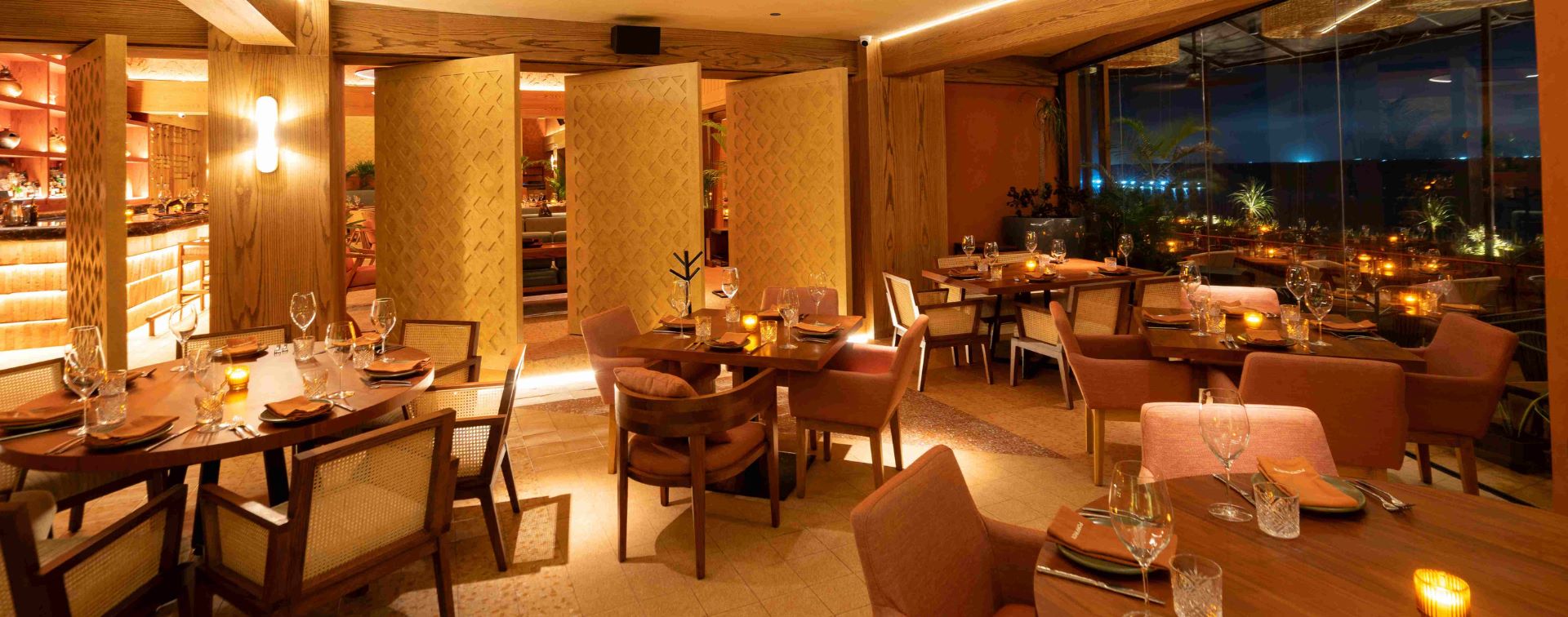 Interior view of a modern, private dining space at Porfirio's Restaurant, featuring warm orange and natural wood tones, patterned sliding doors, and intimate seating arrangements. The room is configured for small corporate groups or executive meetings, showcasing a stylish, private atmosphere. This venue is ideal for high-level MICE discussions, breakout sessions, and exclusive corporate hospitality in Cancún.