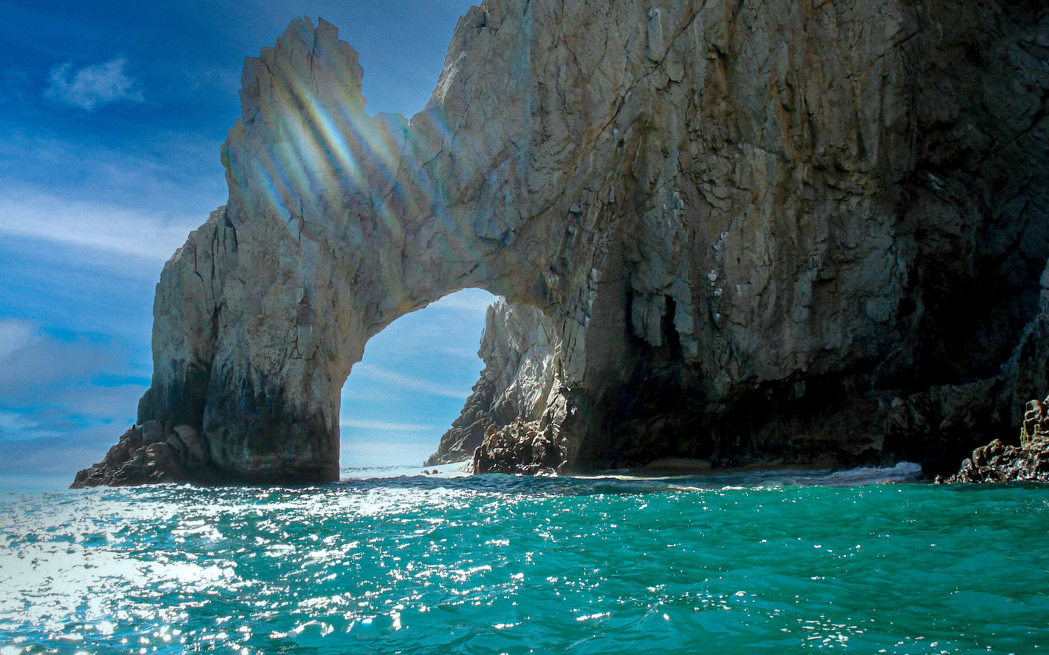 A stunning close-up of the famous Arch of Cabo San Lucas (El Arco) from the water, with sun rays shining through the rock formation. This iconic landmark is a highlight for private boat tours and unforgettable excursions for incentive travel and MICE groups.