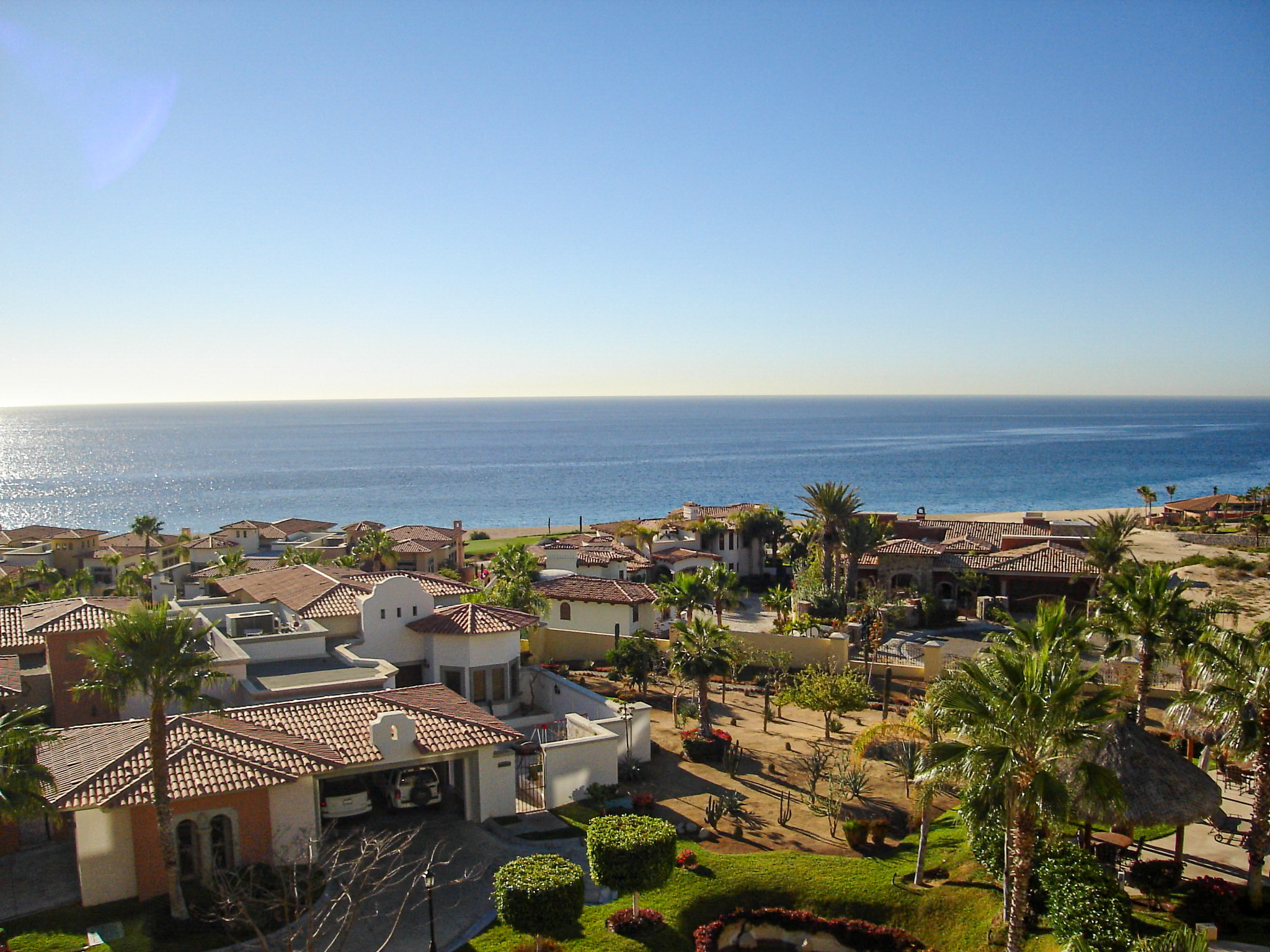 A bright, high-angle view of a luxury Los Cabos resort, featuring lush landscaping, beautiful architecture, and a view of the clear blue ocean. This image perfectly showcases the high-end accommodations available for MICE groups and incentive travel.