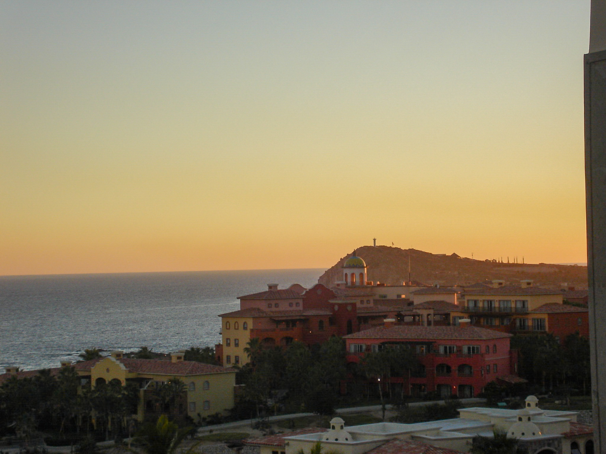 A tranquil, elevated view of Los Cabos resorts and the Pacific Ocean at sunset. This destination is ideal for incentive travel and corporate retreats, offering top-tier accommodations and a perfect setting for relaxation after MICE events.