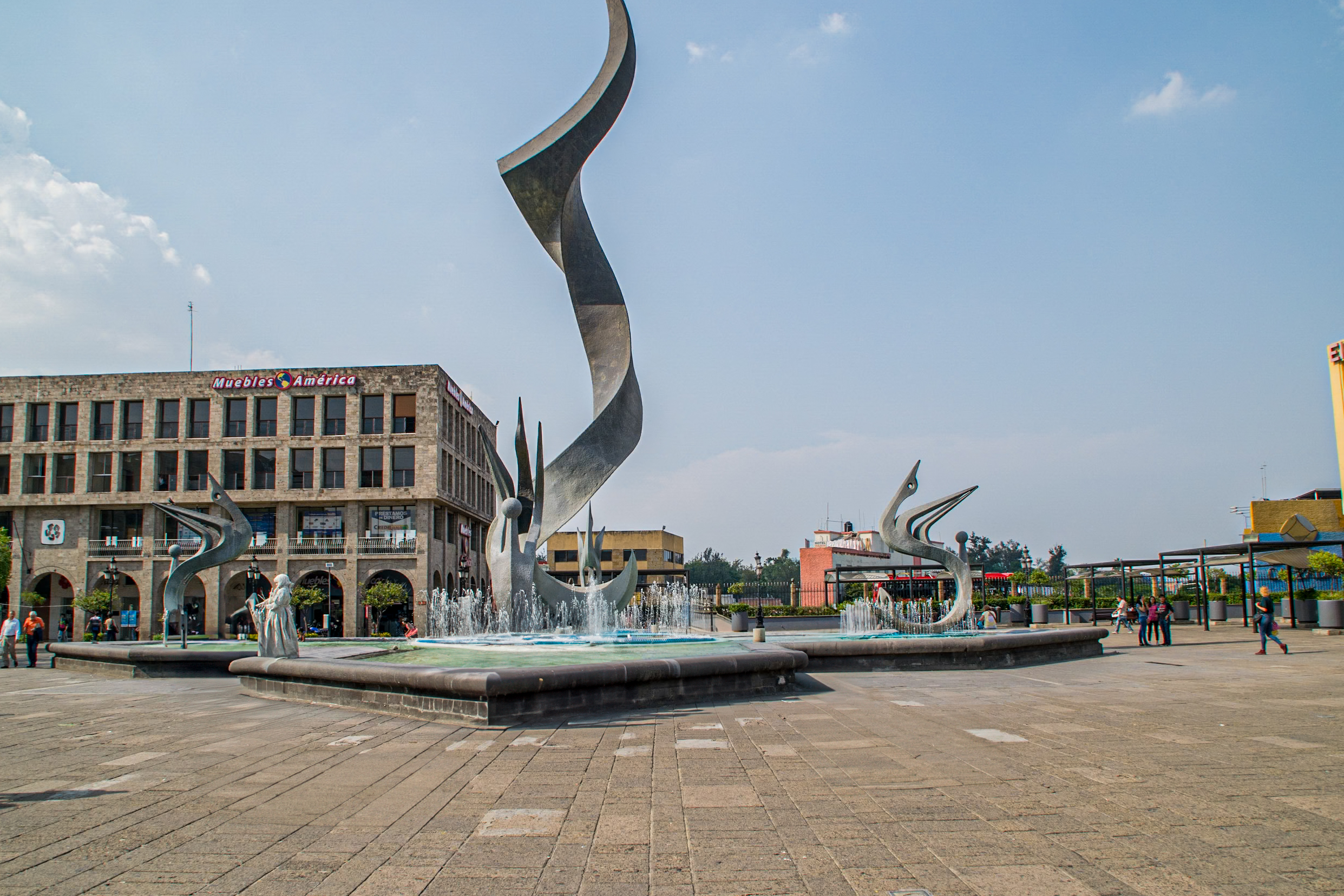 A view of the Guadalajara Cathedral and the central fountain in the Plaza de la Liberación. The photo captures the city's historic charm and cultural appeal, making it an excellent destination for incentive travel, corporate meetings, and MICE events. The Mexican flag waves prominently in the foreground.