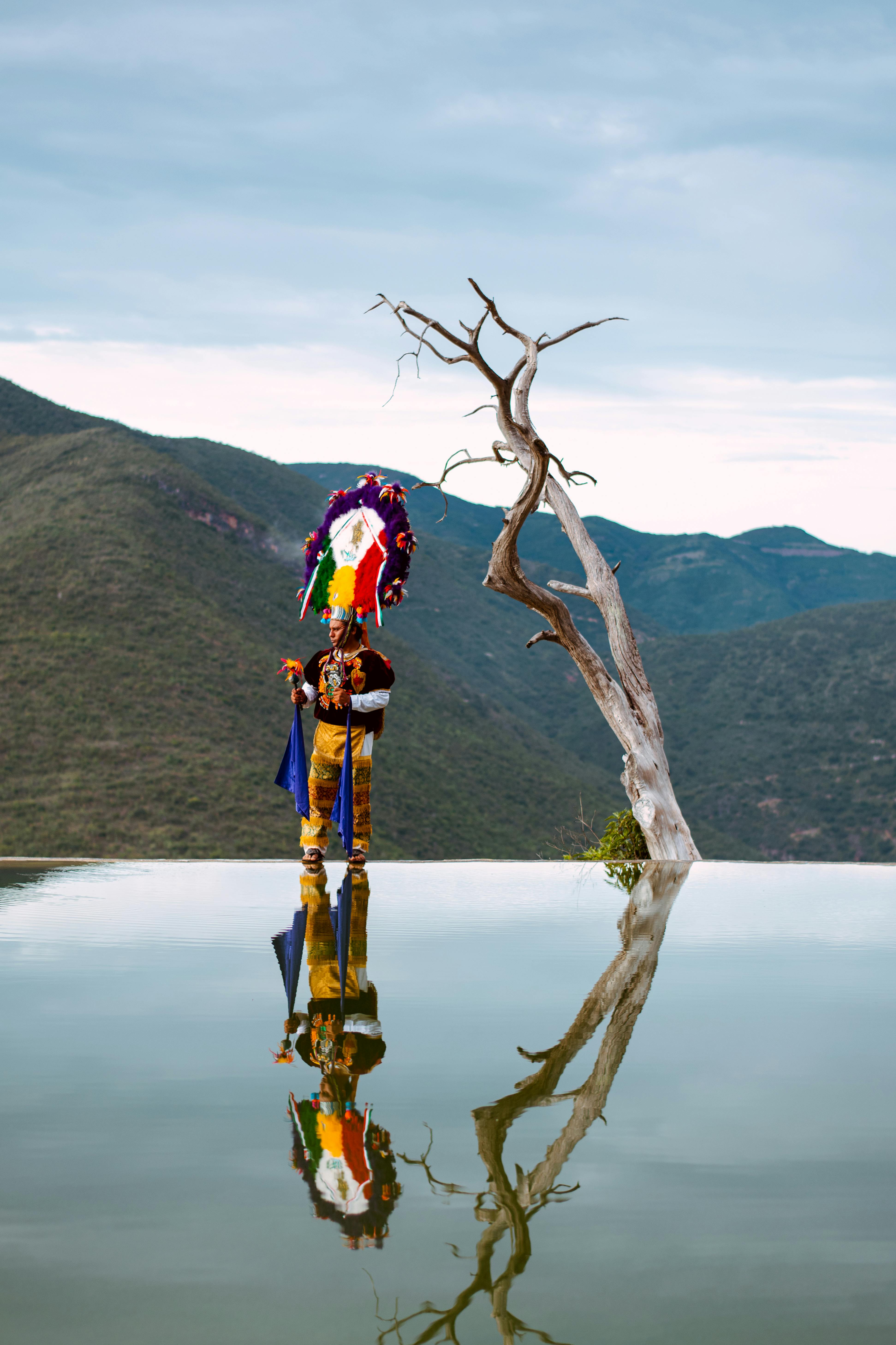 A striking image of a dancer in traditional Oaxacan attire standing on a reflective pool at Hierve el Agua, with stunning mountains in the background. This showcases the unique blend of natural beauty and rich cultural heritage that makes Oaxaca an unforgettable incentive travel destination.