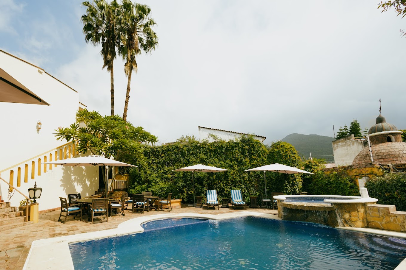 Serene poolside area at Hotel Hacienda Los Laureles Spa in Oaxaca with lounge chairs, umbrellas, and mountain views—ideal for MICE incentive travel and wellness retreats.