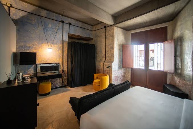 Industrial-style guest room at Hotel Pug Seal Oaxaca with minimalist décor, workspace, and vibrant accents—ideal for MICE attendees seeking creative and comfortable lodging.