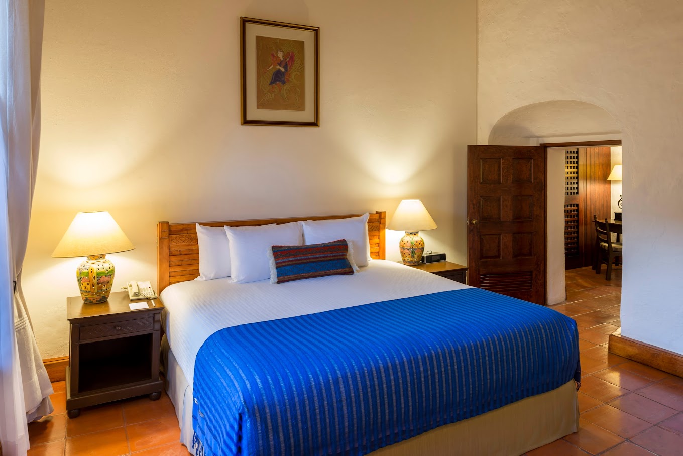 Elegant guest room at Hotel Quinta Real Oaxaca with blue bedspread, ceramic lamps, and warm lighting—ideal for MICE attendees seeking comfort and colonial charm.
