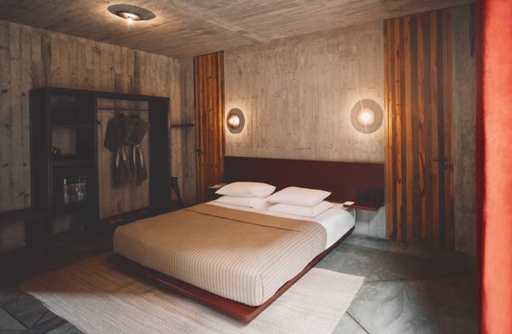 Minimalist guest room at Otro Oaxaca with concrete finishes, warm lighting, and open wardrobe—ideal for MICE attendees seeking stylish, functional lodging in a design-focused hotel.