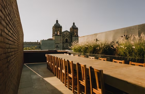 Rooftop dining terrace at Otro Oaxaca with cathedral views, long table setup, and warm lighting—ideal for MICE welcome dinners, networking events, and incentive group experiences.
