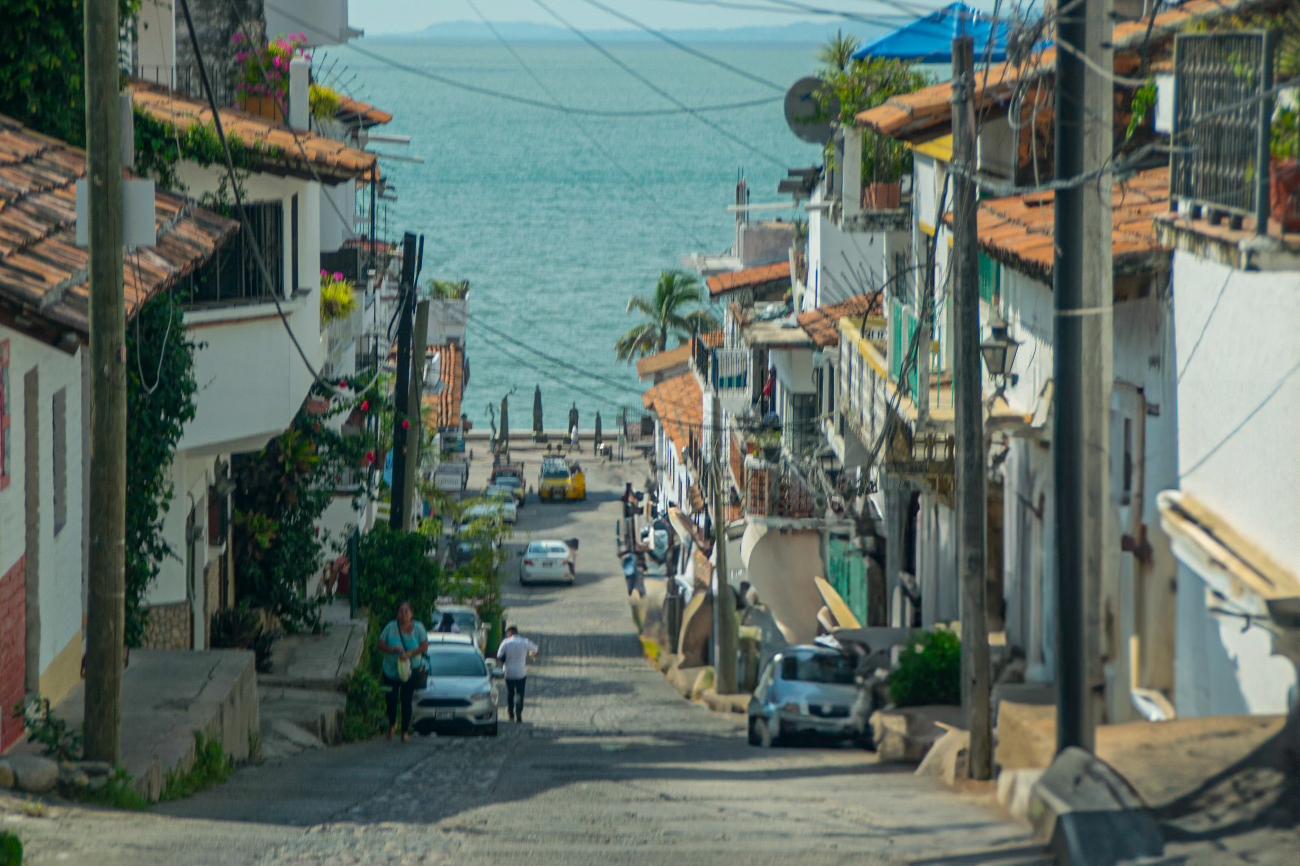 Vibrant street in a Mexican coastal town leading to the ocean, lined with red-tiled buildings and palm trees—ideal for incentive travel and team excursions.